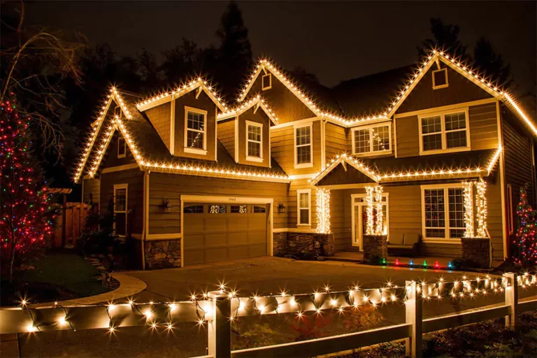 Beautiful two-story home decorated with professional holiday lighting service, showcasing warm white Christmas lights along the roofline and fence in Cypress, TX.