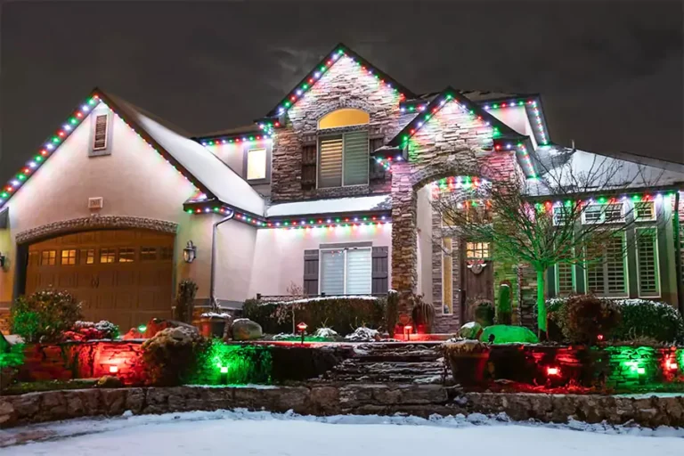 Beautifully decorated house with colorful holiday lights on roofline and landscape, creating a festive look for winter season.