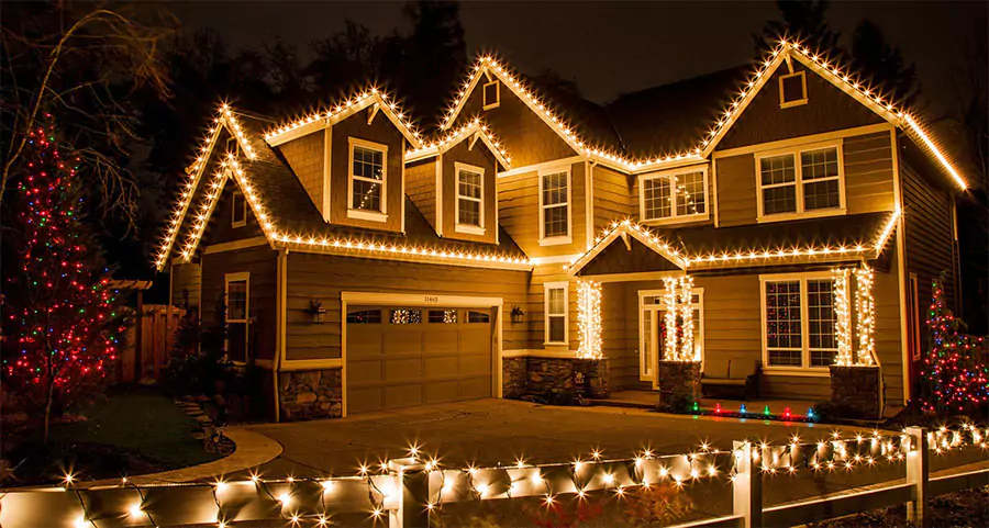 Two-story home decorated with festive holiday lights along the roofline, windows, and entryway, creating a warm, inviting glow at night in Cypress, TX.
