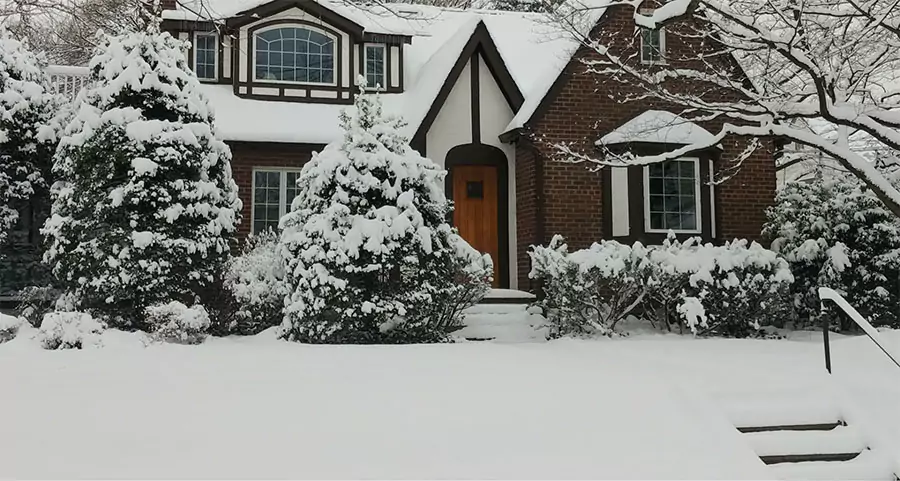 Snow-covered house showcasing winter landscape maintenance benefits in Houston, TX.