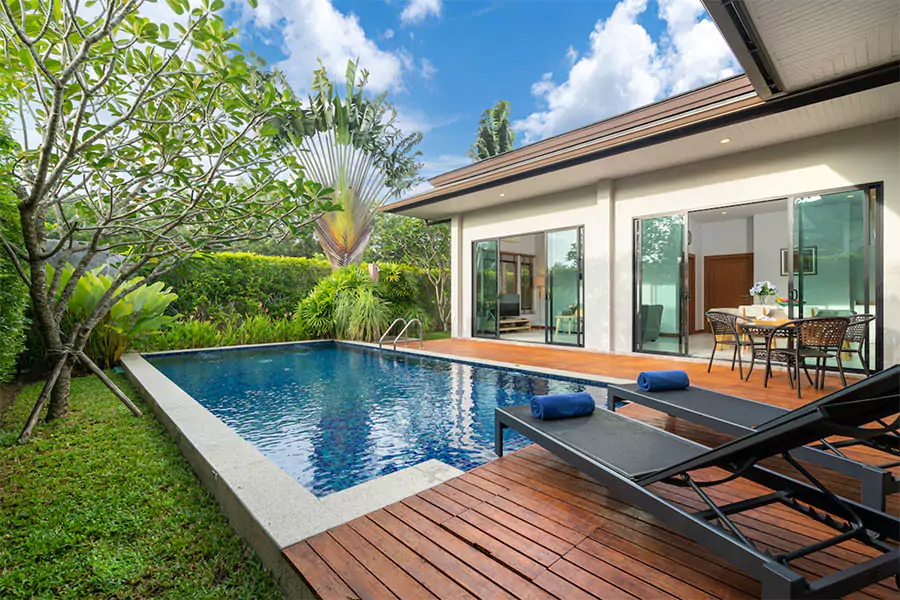 Luxury backyard with modern swimming pool, tropical landscaping, and outdoor seating area in Houston, showcasing winter yard transformation by pool and landscape contractors.