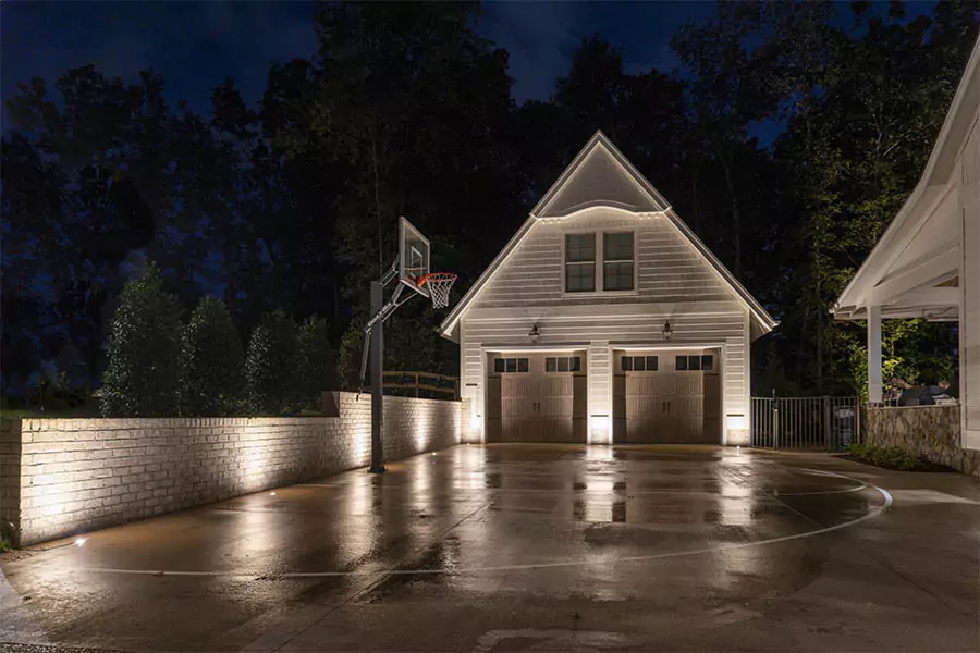Elegant outdoor lighting showcasing a beautifully illuminated driveway and garage, perfect for enhancing curb appeal and security. Learn about the benefits of LED vs. halogen landscape lighting.