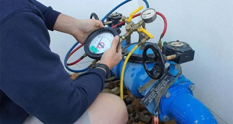 Technician performing backflow testing on irrigation system to ensure water safety compliance