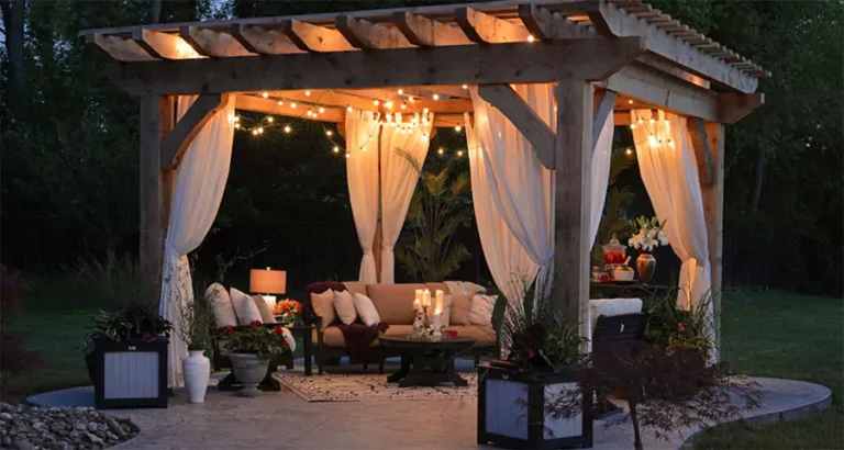 Cozy backyard patio with wooden pergola, string lights, and outdoor lounge furniture for stylish landscape design in Houston, TX