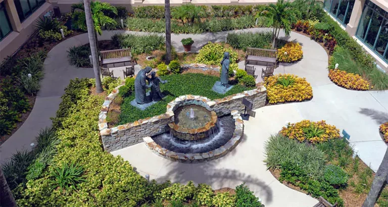 Commercial landscape courtyard with fountain, statues, and tropical plants at a Houston business property