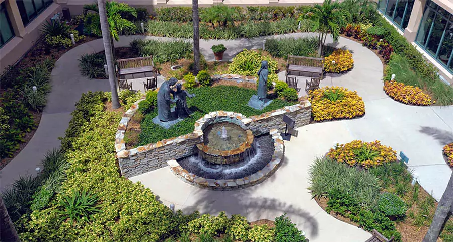 Commercial landscape courtyard with fountain, statues, and tropical plants at a Houston business property