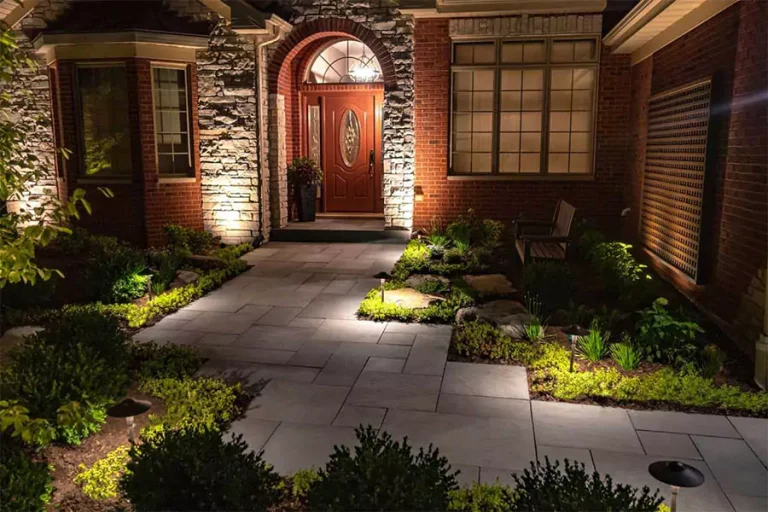Professional landscape lighting illuminating a stone walkway and front entrance of a home at night for enhanced curb appeal and security