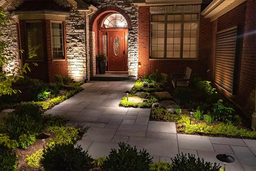 Professional landscape lighting illuminating a stone walkway and front entrance of a home at night for enhanced curb appeal and security