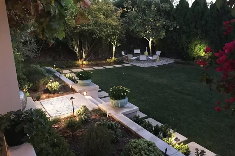 Backyard landscape design with outdoor lighting, stone pathways, garden planters, and seating area in Cypress TX home