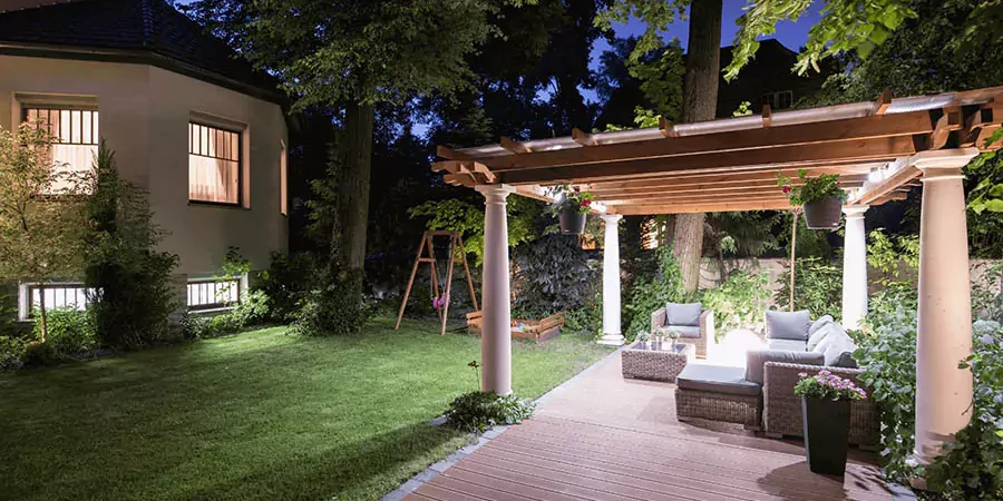 A white house and a covered patio with green big trees