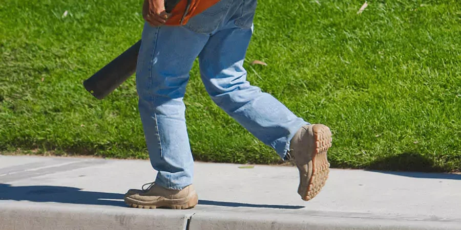 A man wearing gings and shoes and walking aside from a green lawn